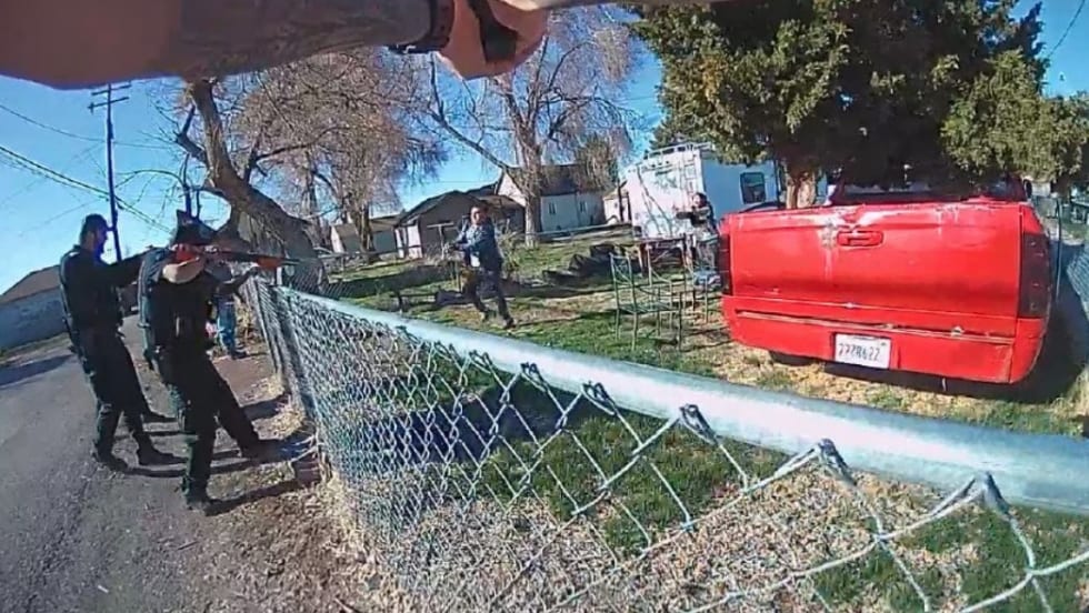 Law enforcement officers near chain-link fence with red truck in residential neighborhood