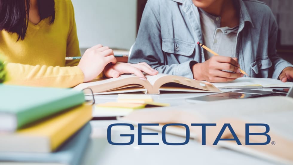 Two students study with books and notes at a desk. Geotab partners with Georgia Tech on $223K traffic data research to improve safety and urban mobility.