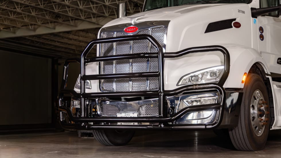 Black grille guard on front of a white tractor trailer, viewed from a front/side angle.