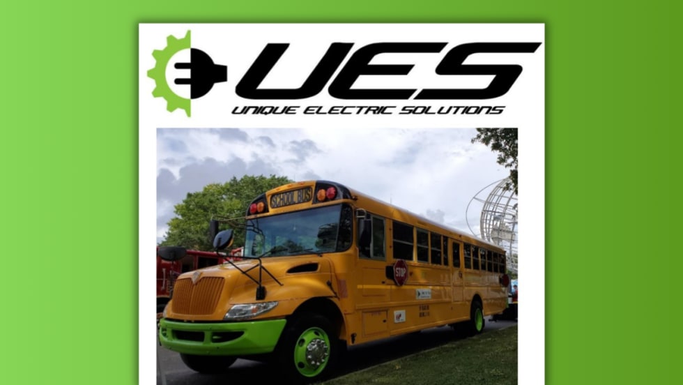 A repowered electric school bus with green wheels and accents, designed by Unique Electric Solutions, parked outdoors under cloudy skies with the company’s logo displayed above the image.