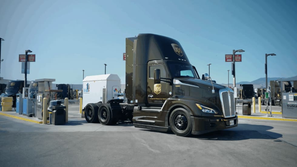 A UPS compressed natural gas (CNG) tractor is parked at a fueling station under clear skies, showcasing the company’s use of alternative fuel vehicles in its delivery fleet.