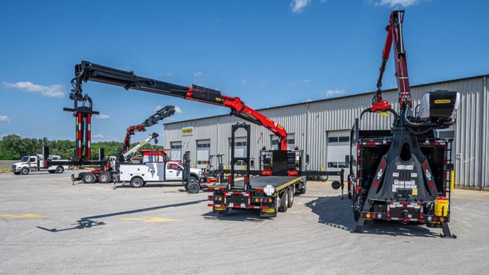 PALFINGER forestry trucks and a mechanic truck with crane parked outside a building.