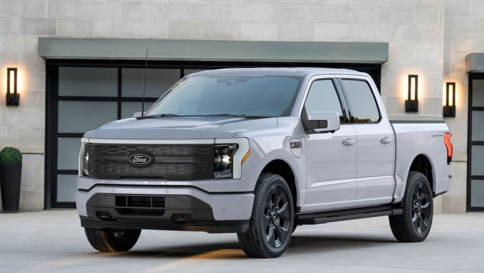 Silver Ford pickup truck parked in driveway of home in front of garage door.