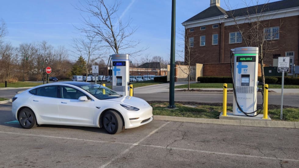 An electric vehicle charges at a public EV charging station outside a municipal building.