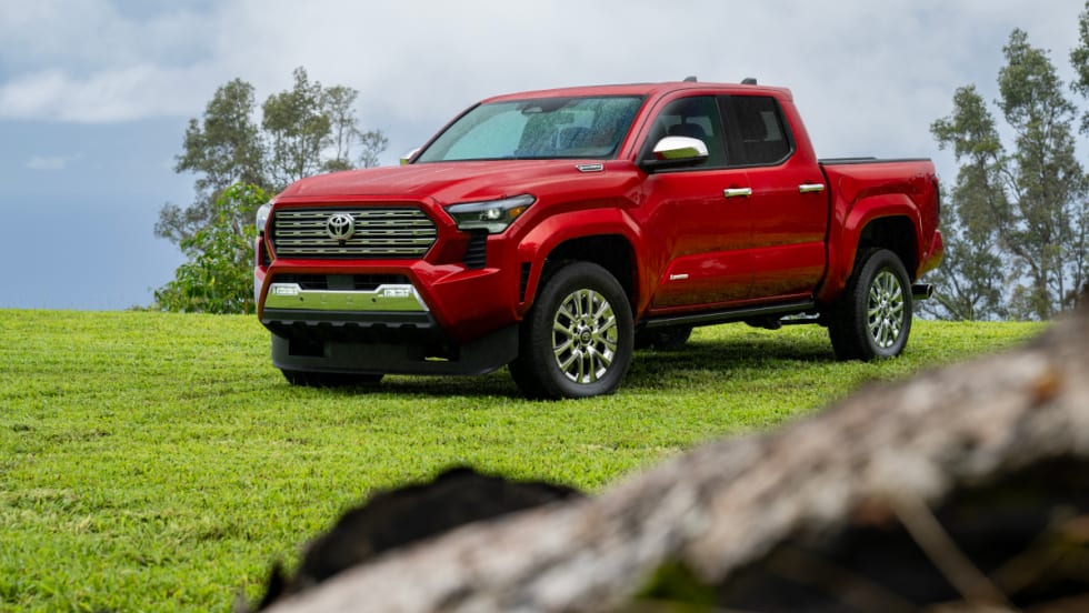 Red four-door Toyota pickup parked in a grassy area.