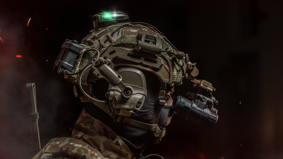 side view of a ballistic helmet in studio setting, black background, with sparks and smoke