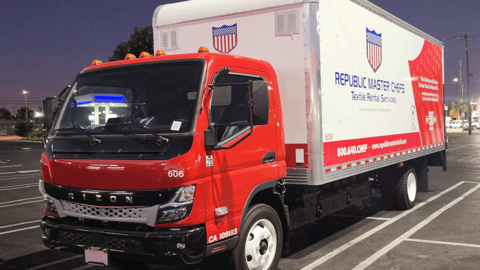 Box truck with a red cab parked in a parking space.