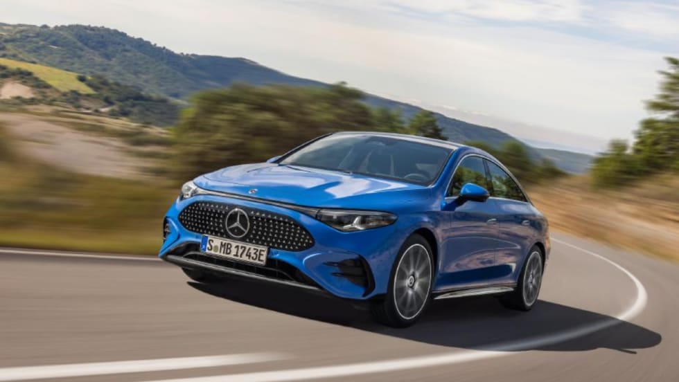 Blue Mercedes-Benz sedan driving on a curving road with blurred hills in the background.