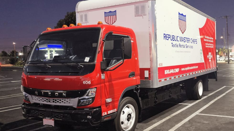 Red Rizon cab-over electric box truck with a Republic Master Chefs-branded cargo box parked in a lot at night.