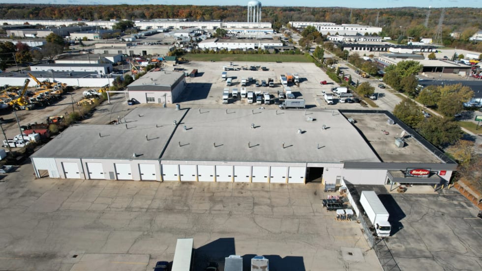 aerial view of an industrial looking large building with large parking areas.