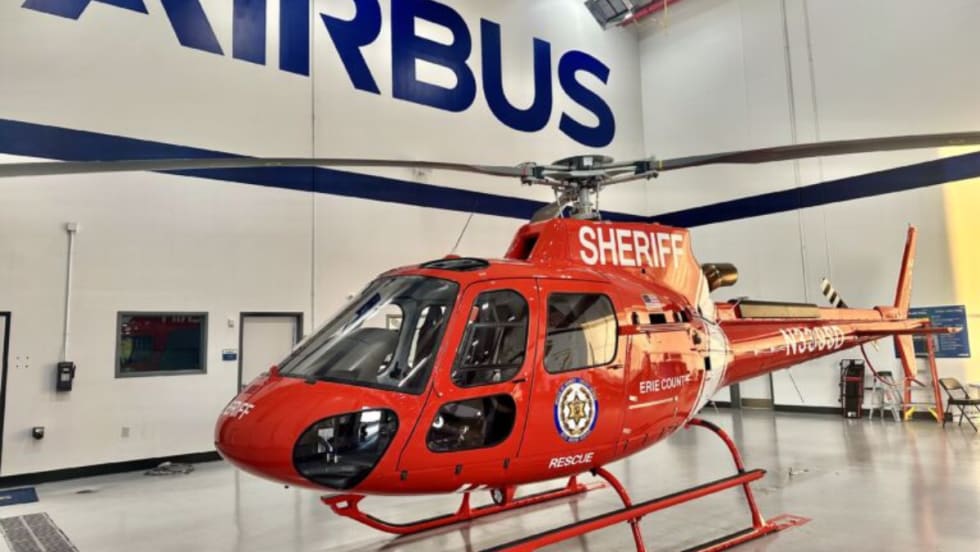 A newly delivered red Airbus H125 helicopter marked “Sheriff” and “Erie County” inside an Airbus facility.
