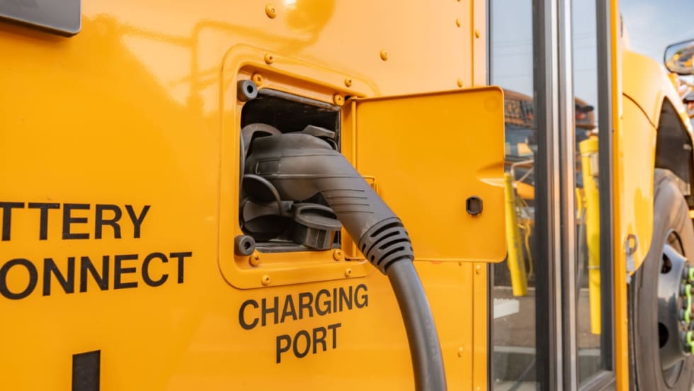 Close-up of an electric school bus charging port with a charging cable connected.