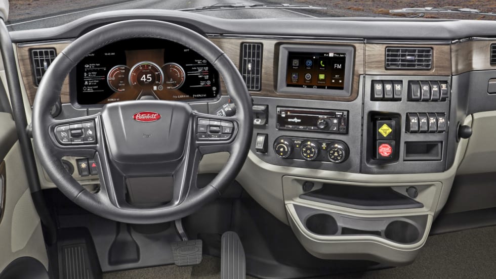 Inside view of a truck cab looking forward at the steering wheel and dash.