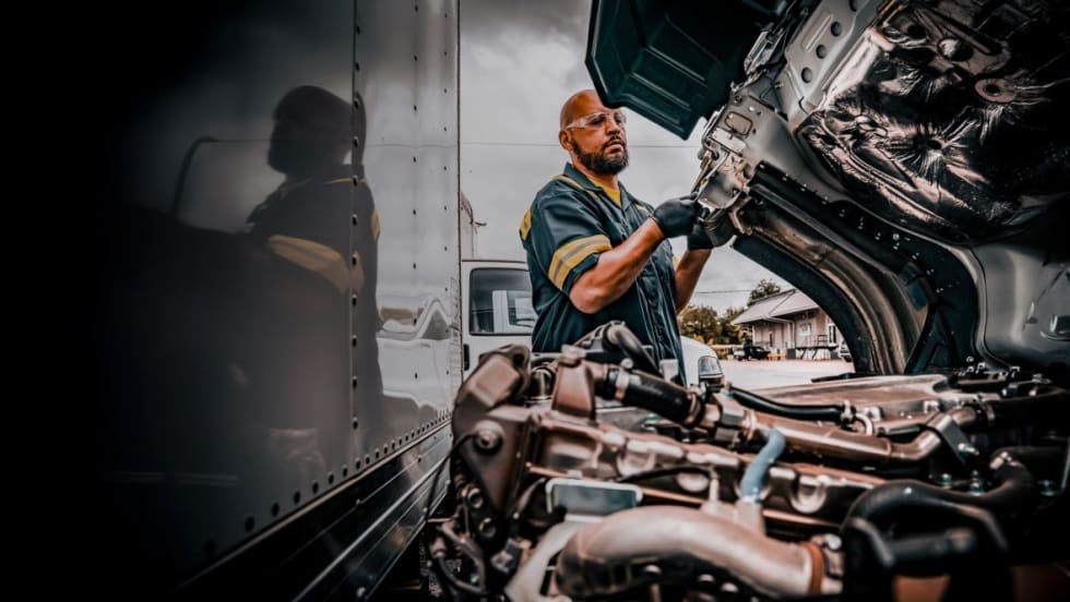 Truck technician working with hood open