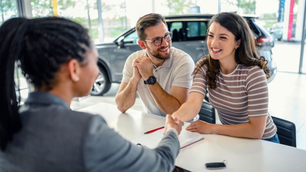 A dealership customer works with an F&I representative at a desk during the vehicle purchase process.