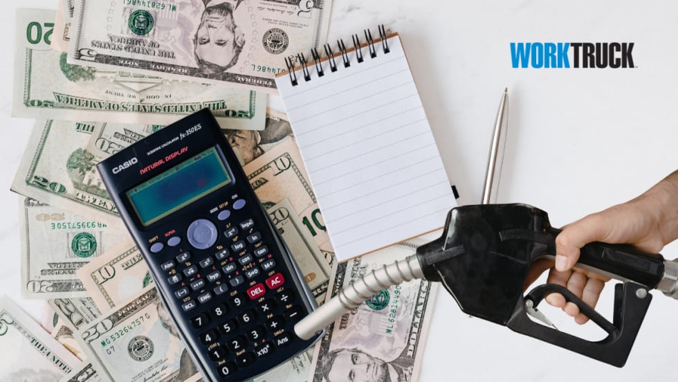 Fuel nozzle over a calculator and money signifying fuels impact on costs