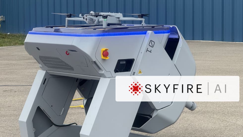 Drone-in-a-box docking station with a quadcopter on top, branded SkyfireAI, positioned outdoors on a concrete surface.