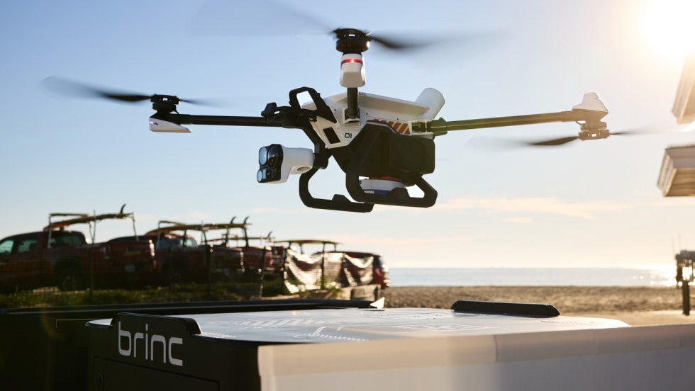 Police drone hovering over its charging nest against a blue sky background.