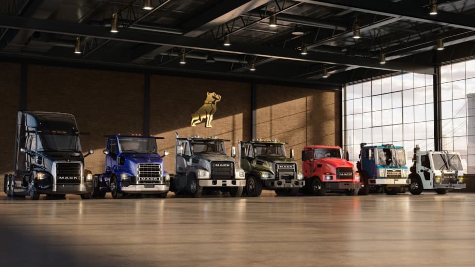 Lineup of Mack Trucks parked inside a warehouse.