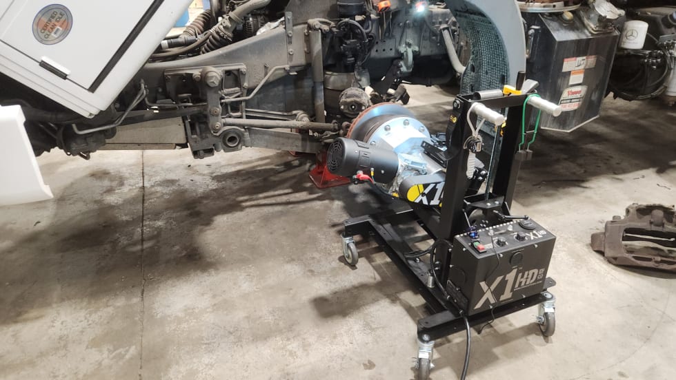 A brake lathe is attached to a truck wheel in a repair shop.