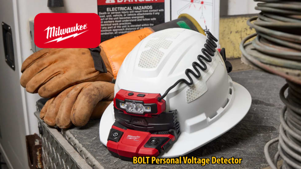 Milwaukee BOLT Personal Voltage Detector mounted on a white hard hat beside work gloves and electrical hazard signage. The safety device features integrated lights and a coiled cable in an industrial work environment.