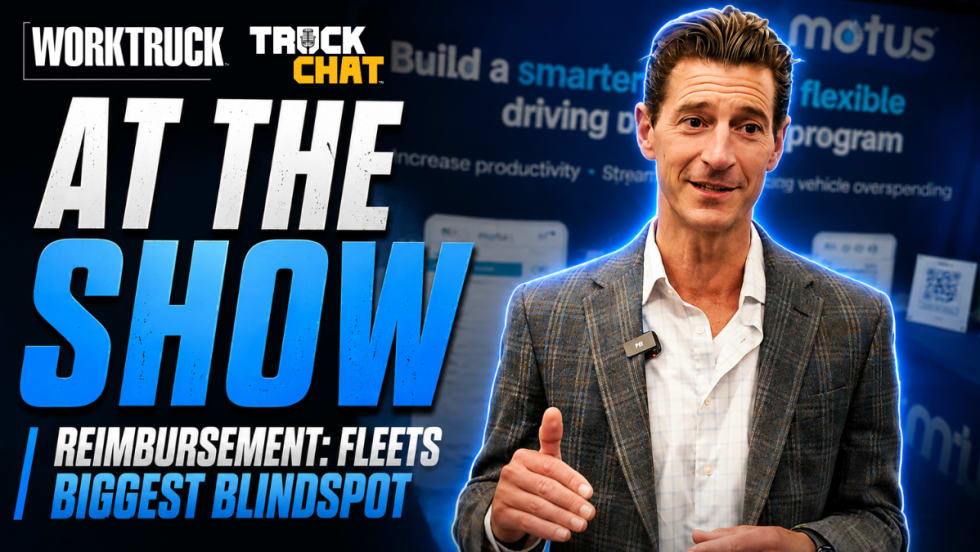 YouTube thumbnail for Work Truck’s Truck Chat series. Large headline text on the left reads “AT THE SHOW” with a subheadline, “Reimbursement: Fleets Biggest Blindspot.” On the right, a man in a gray plaid blazer and white shirt speaks while gesturing with his hand, wearing a wireless microphone clipped to his jacket.
