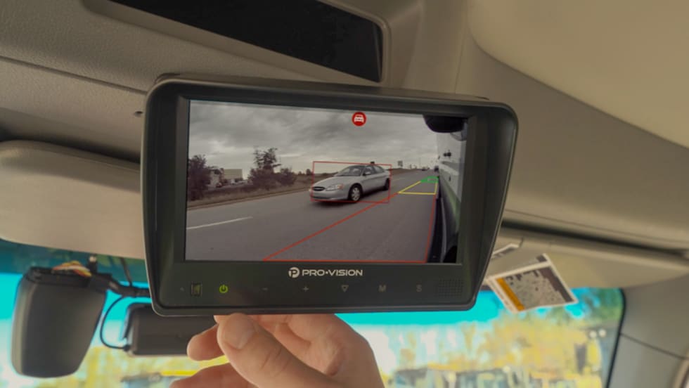 Pro-Vision monitor mounted inside a work truck displays a side camera view with AI detection highlighting a nearby vehicle during a lane change.