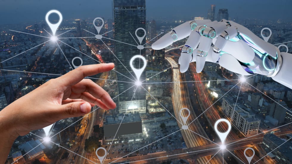 Illustration of a human hand reaching toward a robotic hand over an aerial view of a city at dusk, with interconnected location pins and network lines symbolizing AI, telematics, connected fleet technology, and data-driven transportation.