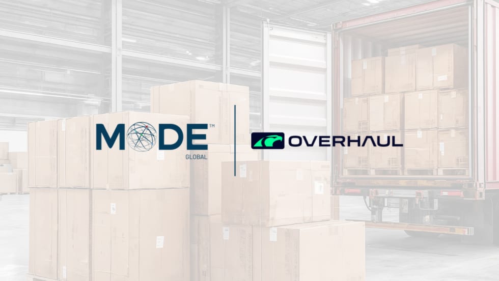 MODE Global and Overhaul logos displayed over a warehouse scene with stacked shipping boxes and a loaded trailer, illustrating a logistics technology partnership focused on freight visibility and supply chain operations.