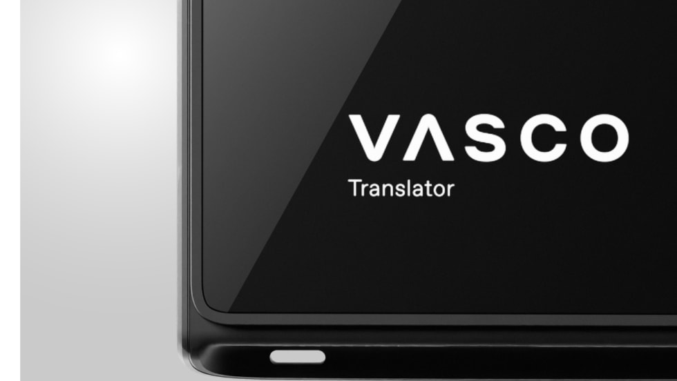 Close-up of a black Vasco Translator device displaying the white Vasco logo and “Translator” text on its screen.
