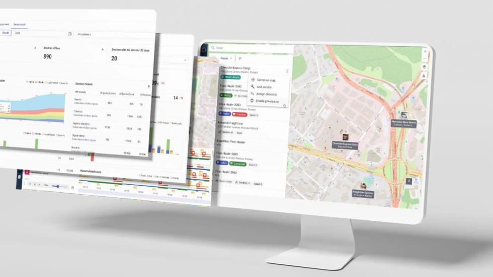 Fleet management software displayed on a computer monitor, showing vehicle tracking maps, device status, fleet analytics, charts, and operational data dashboards.