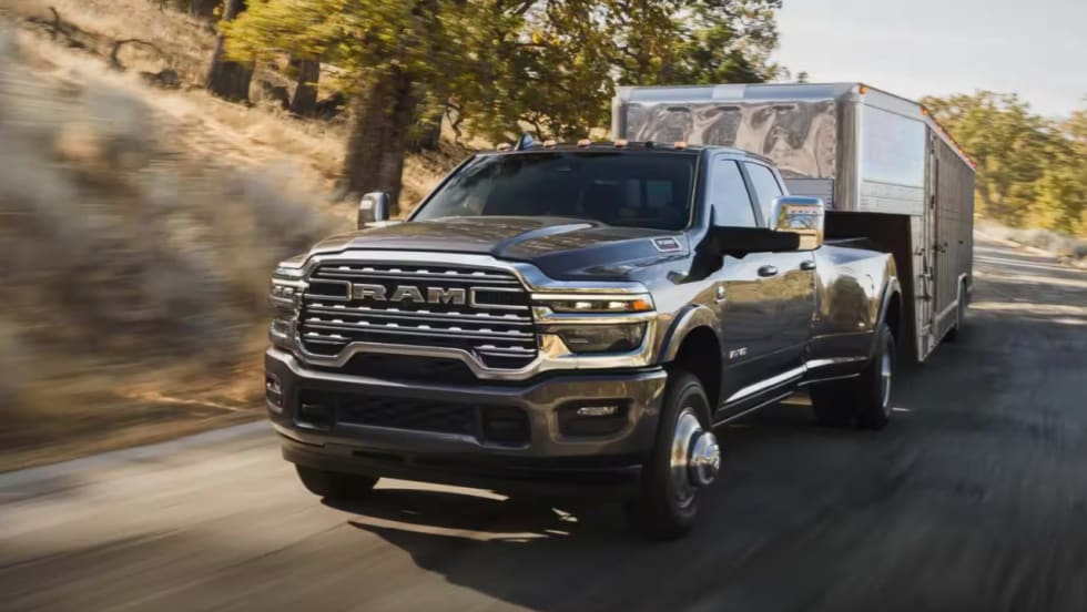 Ram 3500 Heavy Duty pickup truck towing an enclosed cargo trailer along a paved road, showcasing the truck's towing capabilities.