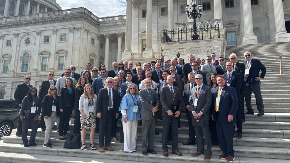 a large group of people stand together on the steps of the U.S. Capitol building
