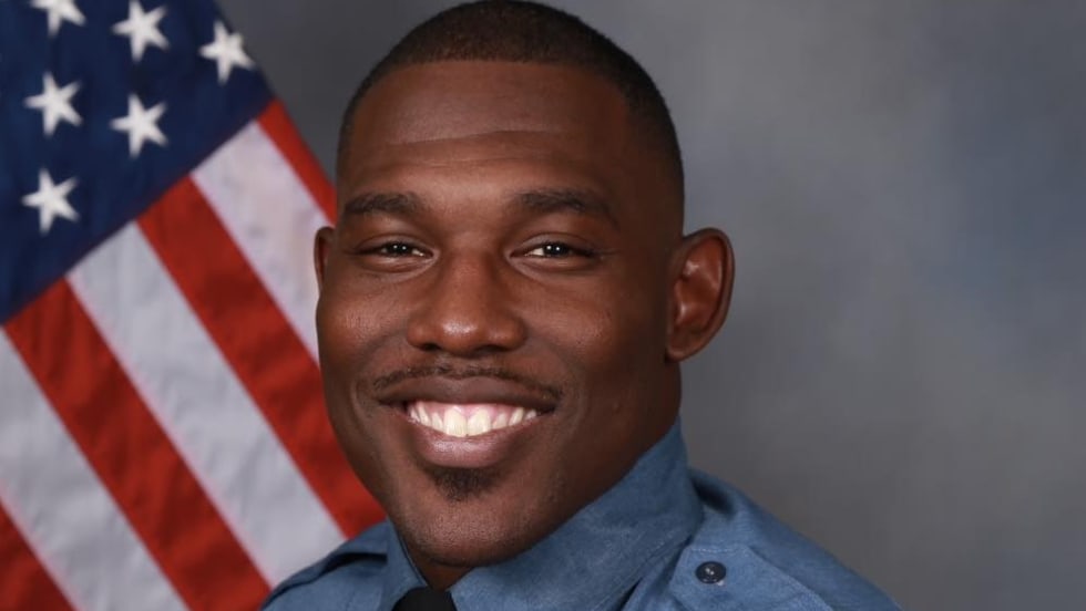 Smiling sheriff's deputy in blue uniform with American flag background