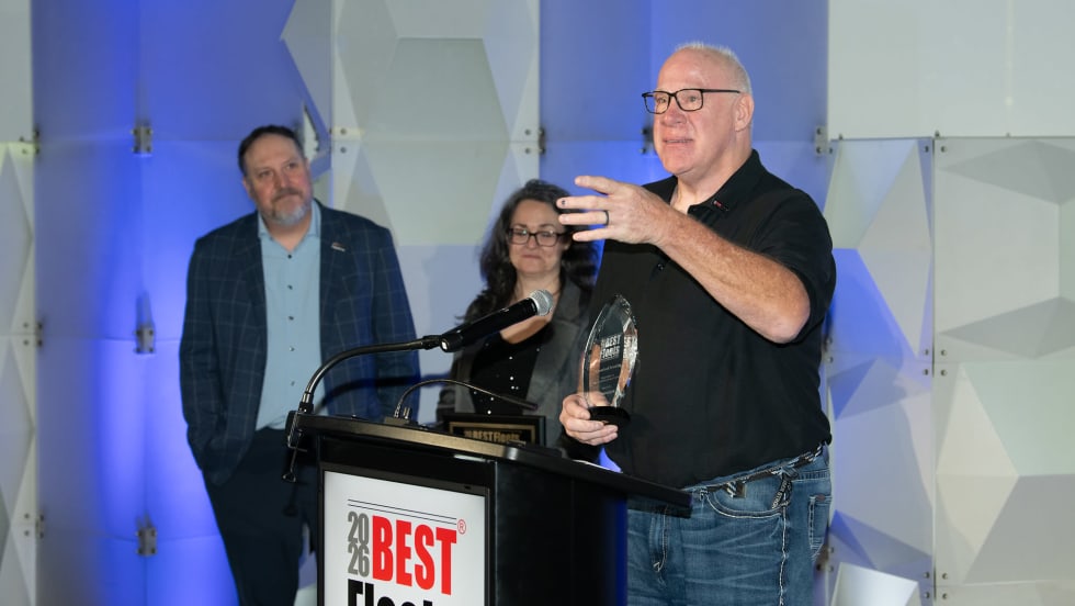 Photo of truck driver at podium holding award