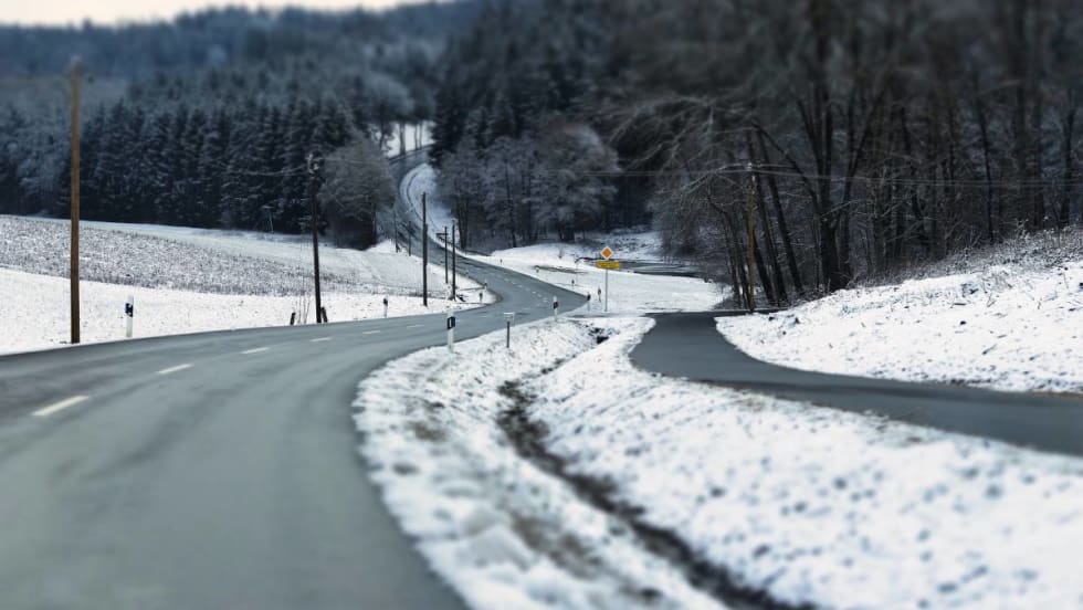 A long snowy road goes uophill.