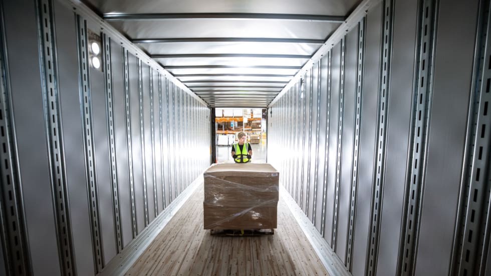 Empty trailer with worker loading a pallet of cargo