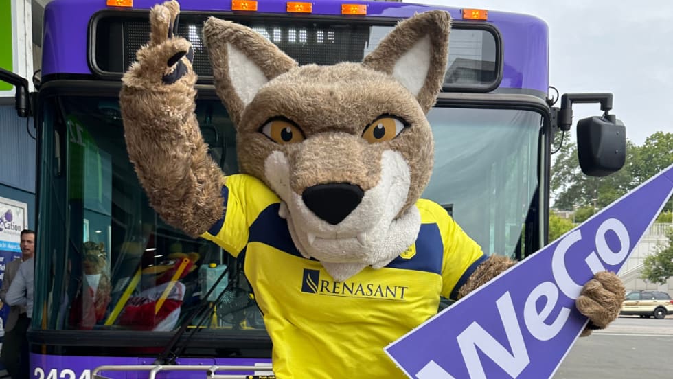Nashville SC mascot poses in front of a purple WeGo Transit bus.