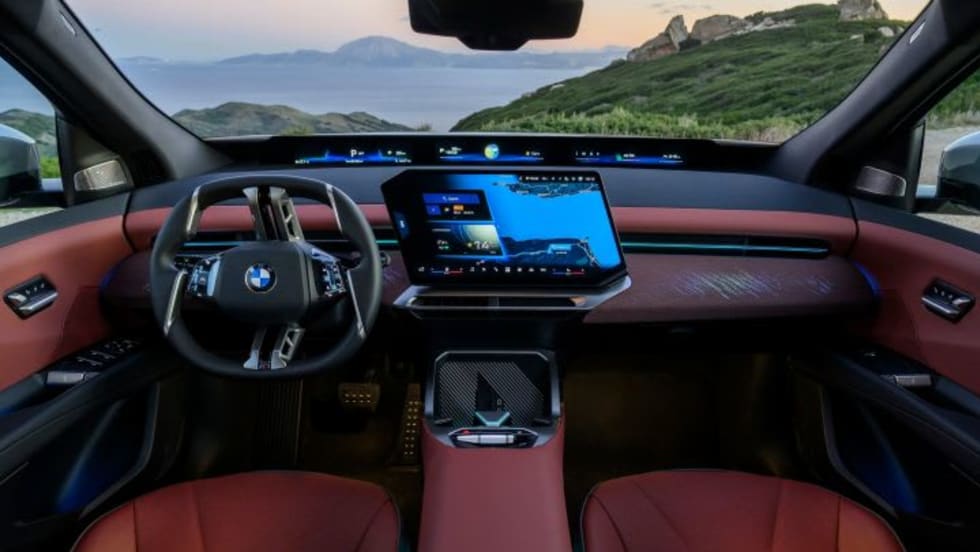 Interior of BMW ix3 electric SUV with hilly landscape seen through windshield