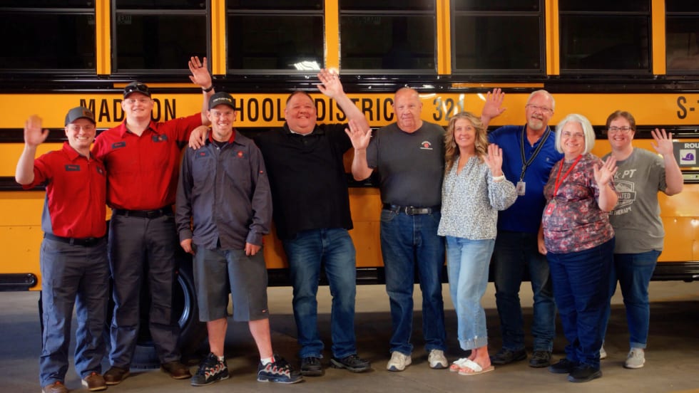 The transportation team in Madison, WI, stands in front of a district school bus