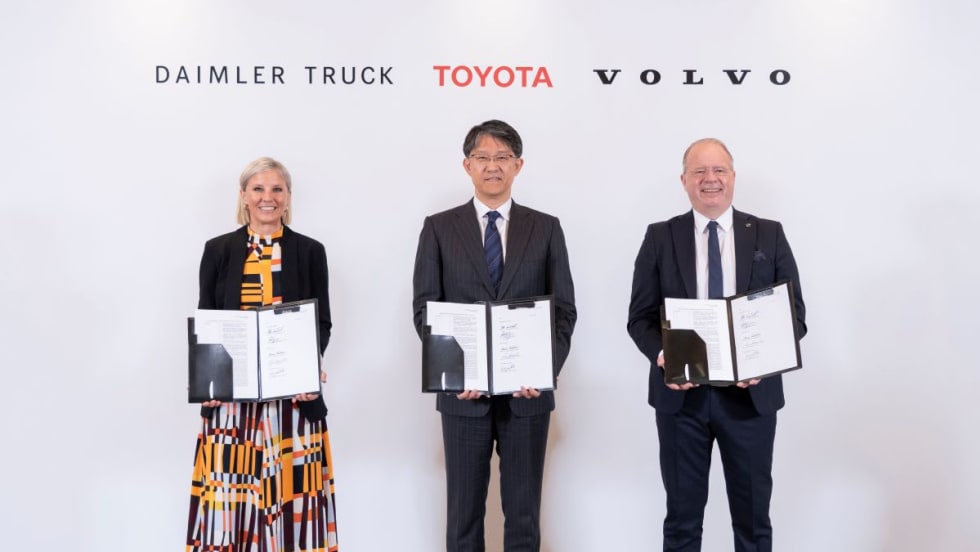 Three CEOs pose displaying binders with memorandum of understanding