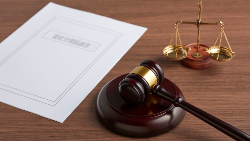 on a desk, a piece of paper, a gavel, and the scales of justice
