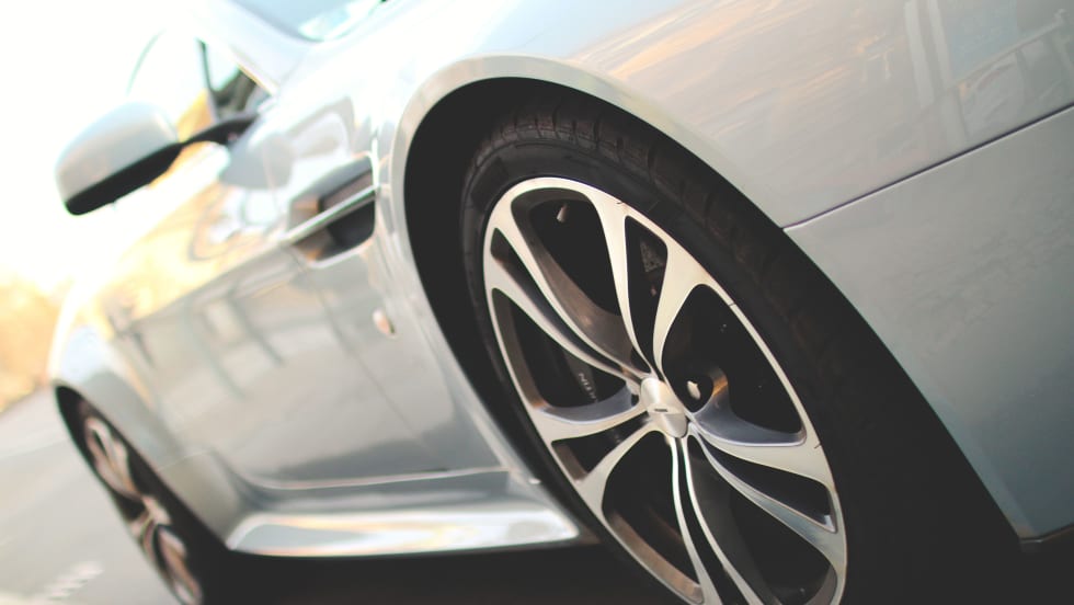 Closeup photo of a new white car on a road from the driver's side 