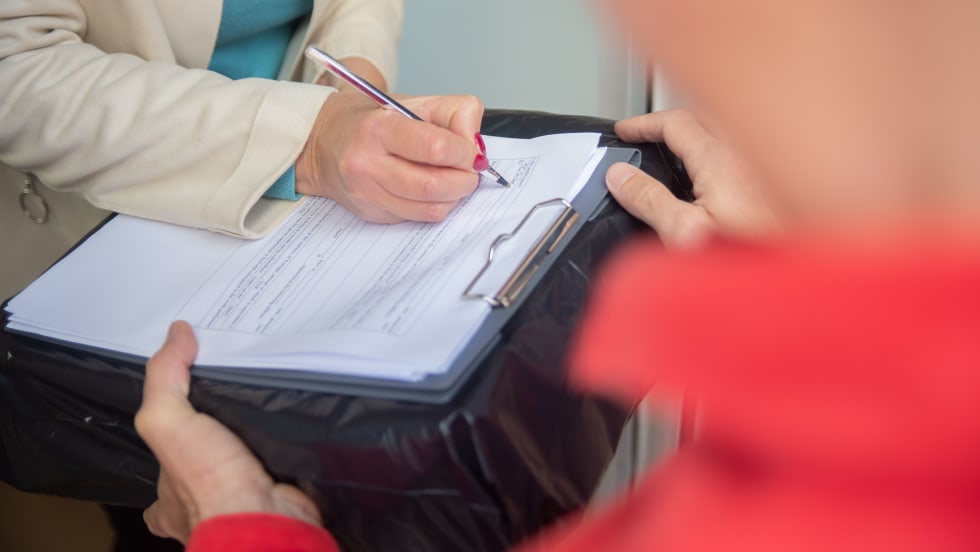 Woman signing a form as a man holds it for her