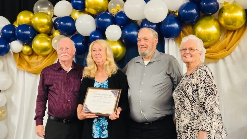 Frances Theiring stands with three other people holding an award