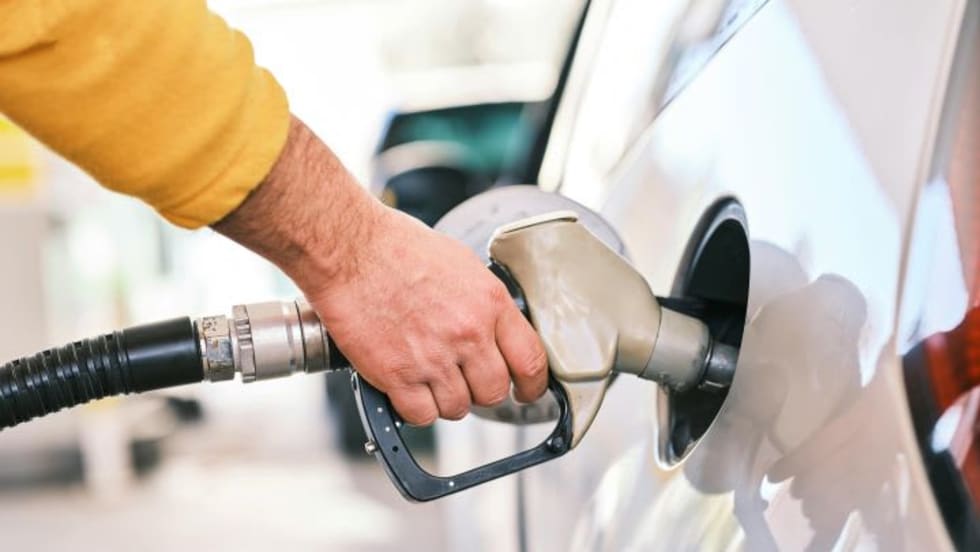 Man's hand holding gas pump in fuel tank of white car
