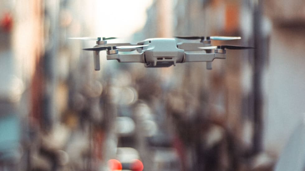 Drone flying in front of blurry background.
