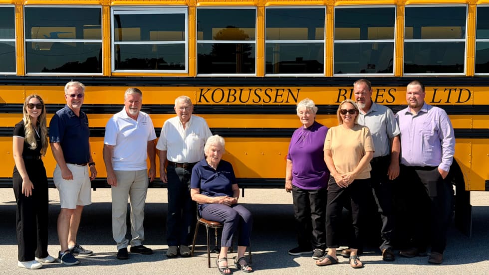 Multiple generations of the Kobussen family posing in front of a school bus.