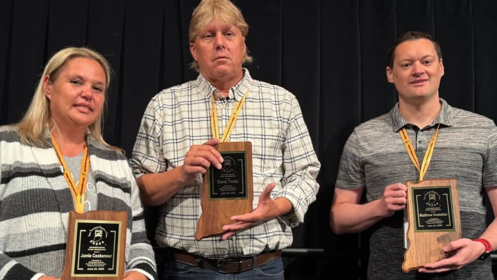Three award winners pose with their awards.
