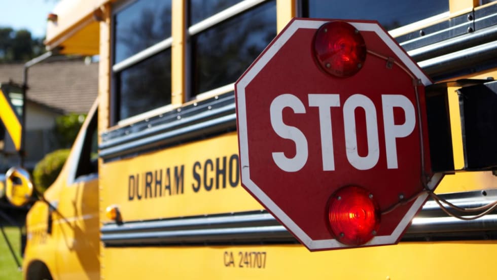 A Durham School Services bus with its stop arm extended.